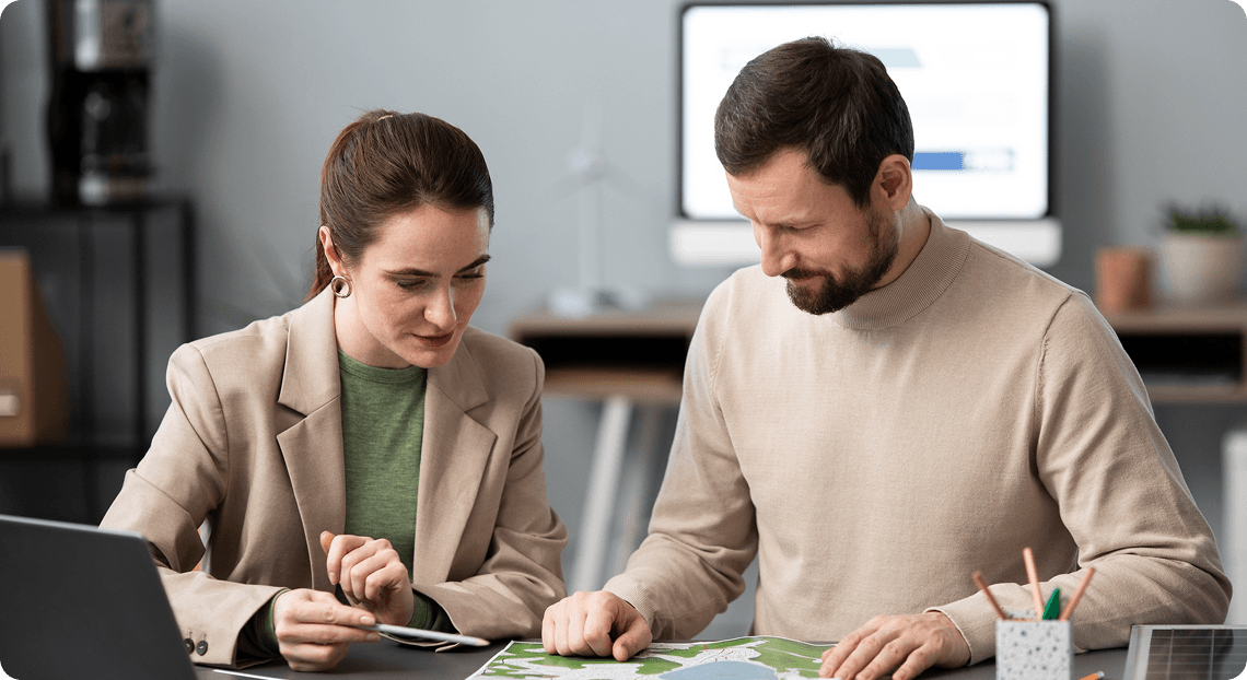 Two colleagues reviewing plans together at a desk